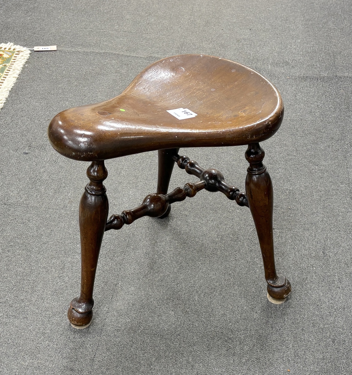 A George III style mahogany saddle seat three legged stool, width 41cm, depth 41cm, height 42cm